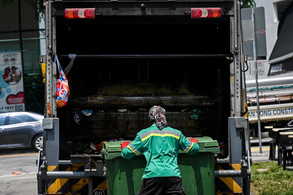 Pekerja sanitasi dengan cekap membuang sampah ke dalam trak angkut sampah di Serangoon Road.