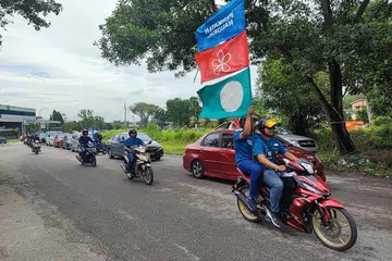 KIAN HANGAT: Seorang pembonceng motosikal mengibarkan bendera Perikatan Nasional (biru) dan dua parti yang membentuknya, Parti Pribumi Bersatu Malaysia (merah) dan Parti Islam SeMalaysia (PAS) di Ipoh, Perak, dengan bahang PRU15 kian terasa di serata Malaysia. - Foto BH oleh NORMAN SAWI