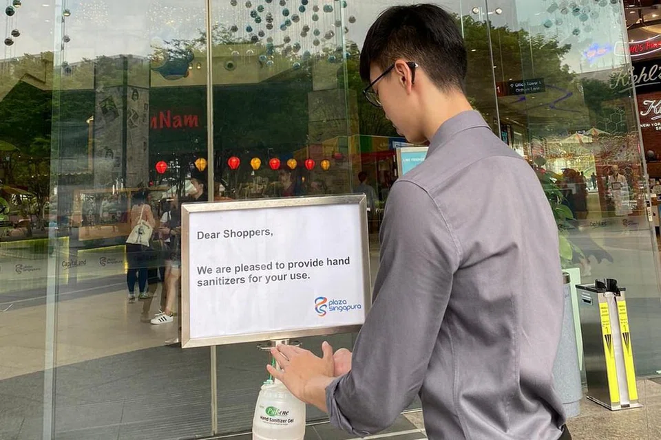 JAGA KEBERSIHAN DIRI: Seorang pengunjung di Plaza Singapura sedang menggunakan sanitiser tangan disedikan di pintu masuk sebelum memasuki pusat belibelah itu. - Foto CAPITALAND