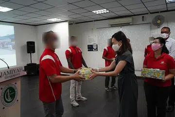TERIMA HABUAN: Seorang penghuni Darul Islal, Encik Ahmad (bukan nama sebenar), menerima kotak hadiah daripada AP GRC West Coast, Cik Rachel Ong, dengan disaksikan pengerusi Interlace Resident Network, Cik Joyce Mehar (kanan). - Foto JAMIYAH SINGAPURA