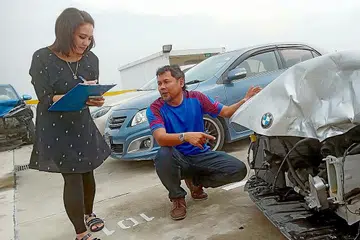 TEMBUSI BIDANG DIKUASAI LELAKI: Cik Juliana, dibantu penolong pengurus bengkel Mohd Dawood Nadzim, memeriksa kereta yang remuk bahagian depannya untuk menilai, menaksirkan kerosakan dan menguruskan tuntutan insurans. - Foto BM oleh SAINI SALLEH