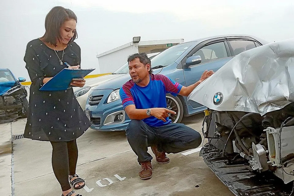 TEMBUSI BIDANG DIKUASAI LELAKI: Cik Juliana, dibantu penolong pengurus bengkel Mohd Dawood Nadzim, memeriksa kereta yang remuk bahagian depannya untuk menilai, menaksirkan kerosakan dan menguruskan tuntutan insurans. - Foto BM oleh SAINI SALLEH