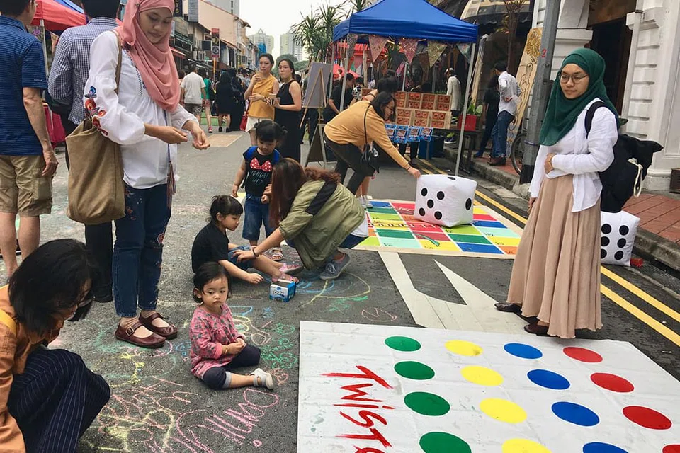 BEBAS BERKREATIF: Anak kecil, Maryam Zulhilmy, 18 bulan, dilihat bebas menconteng permukaan jalan raya di Arab Street sementara ibunya, Cik Nadia Ramlee (kanan) mencuba permainan 'Twister', antara aktiviti di Park(ing) pada Sabtu lalu. - Foto BH oleh HANIM MOHD SALEH 