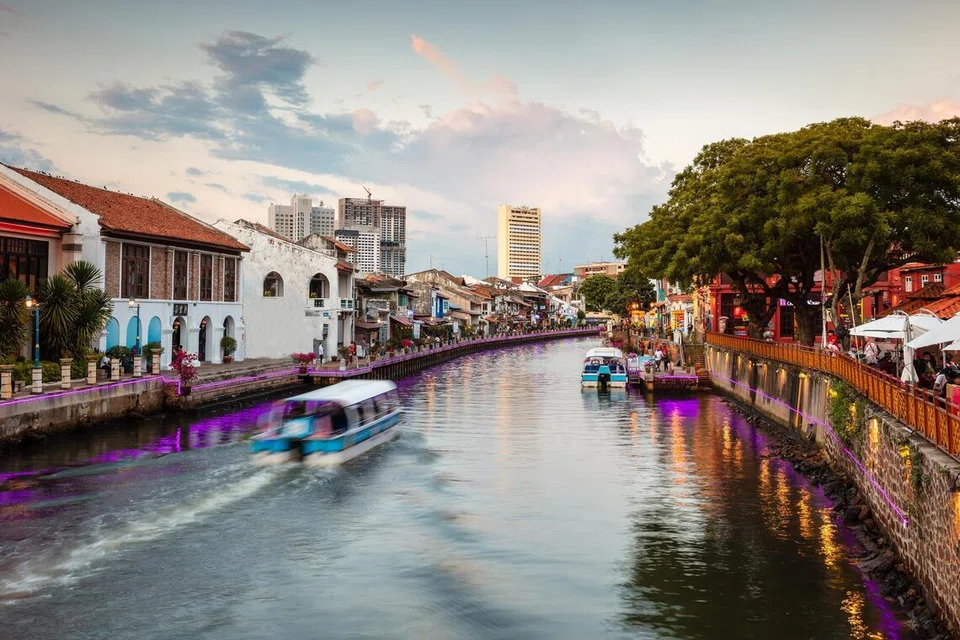 Bot melayari sungai di Melaka, Malaysia, sewaktu matahari terbenam.