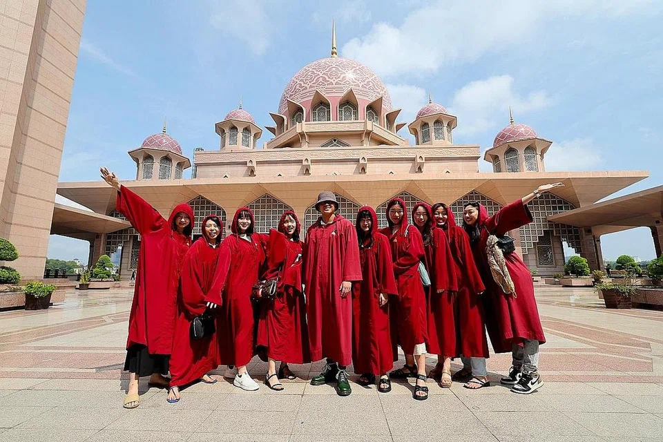 KENANGAN DI MALAYSIA: Para pelancong dari Jepun merakamkan gambar kenangan berlatar belakangkan Masjid Putra. - Foto BERNAMA