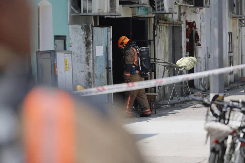 Anggota Pasukan Pertahanan Awam Singapura (SCDF) memasuki unit yang terbakar melalui pintu belakang.