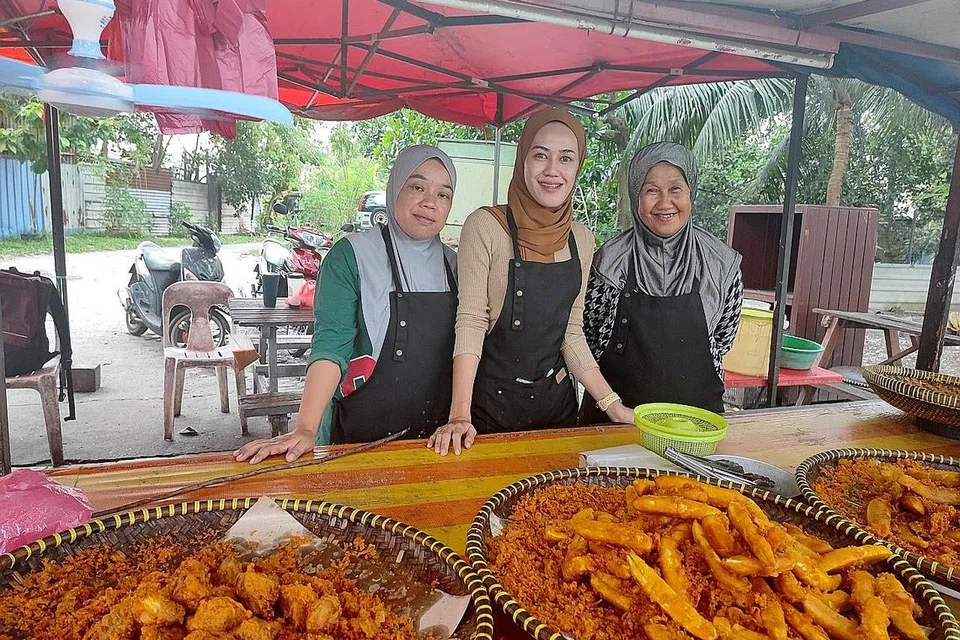 PENDAPATAN BERKURANGAN: Cik Nur Sezlin (tengah) bersama kakaknya, Cik Afdah Ilis, dan ibu mereka, Cik Sabariah Samad. Pendapatan keluarga ini hasil penjualan kudapan goreng berkurang sekitar 50 peratus sejak pandemik Covid-19. - Foto\ BH oleh NORMAN SAWI