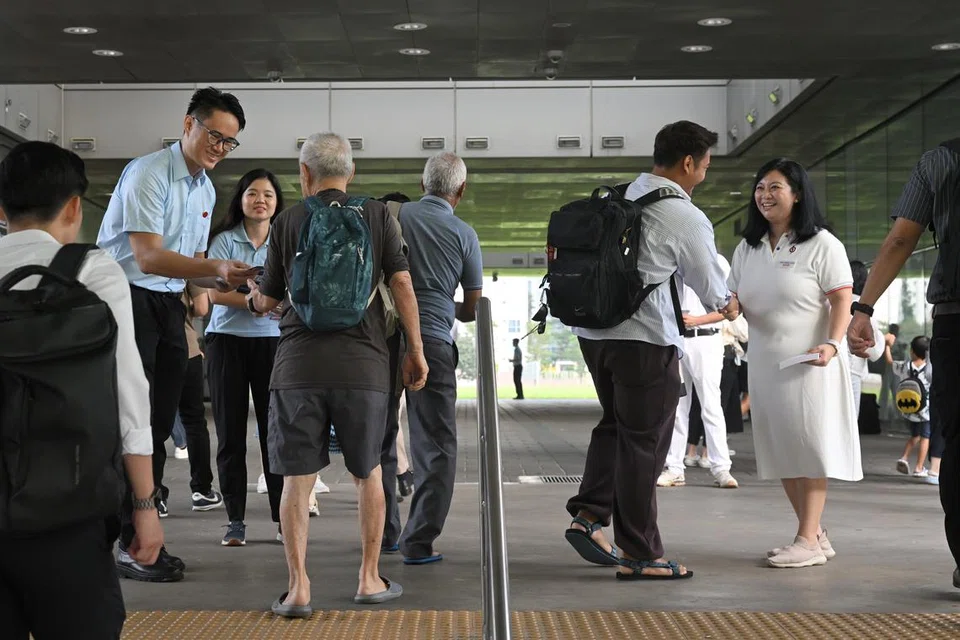 Anggota pasukan Parti Pekerja (WP) di GRC Punggol, Encik Jackson Au (kiri), dan anggota pasukan Parti Tindakan Rakyat (PAP) di GRC Punggol, Cik Yeo Wan Ling (kanan), bersama-sama memberi risalah parti masing-masing dan beramah mesra dengan penduduk di pusat pertukaran bas Punggol.