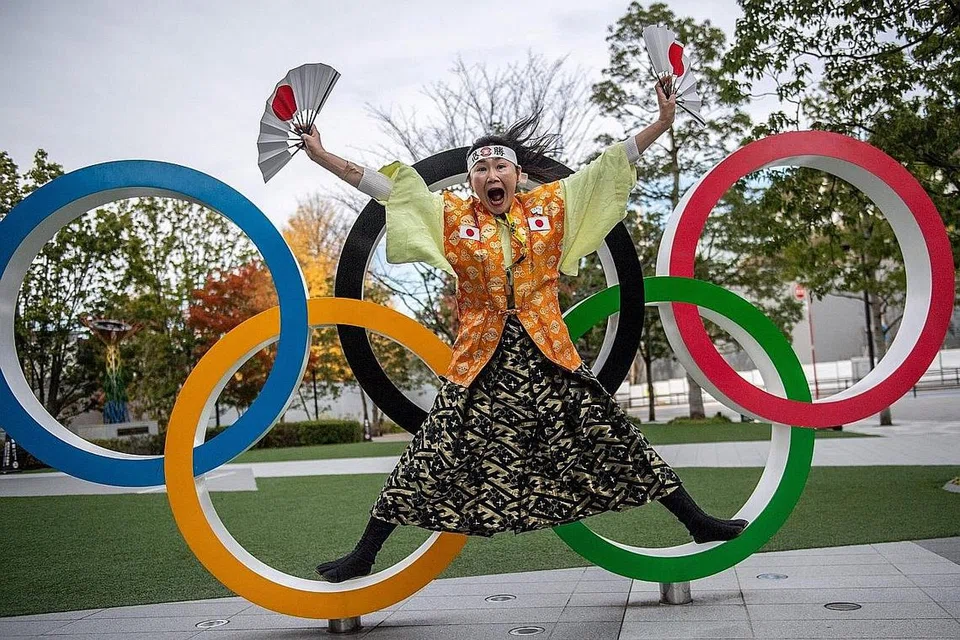 MASIH TANDA TANYA: Seorang peminat Sukan Olimpik Kyoko Ishikawa bergaya di depan sebuah pemasangan cincin Olimpik di luar Stadium Nasional Tokyo. - Foto AFP