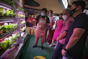 BANDAR EKO: Encik Masagos, yang ditemani penasihat pertubuhan akar umbi Tampines (dari kiri) Dr Koh Poh Koon, Cik Cheng Li Hui dan Encik Desmond Choo, melihat hidroponik menegak di reruai pertunjukan dengan relawan eko Our Tampines Hub, Encik Rian Naim (tengah), 17 tahun, di Our Tampines Hub semalam. - Foto BM oleh JASON QUAH