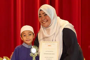 Pengurus Kanan di Andalus cawangan Timur, Ustazah Zulaikha Ishak, bersama seorang pelajar ketika Majlis Anugerah Pelajar Cemerlang yang berlangsung pada Mac 2024.  