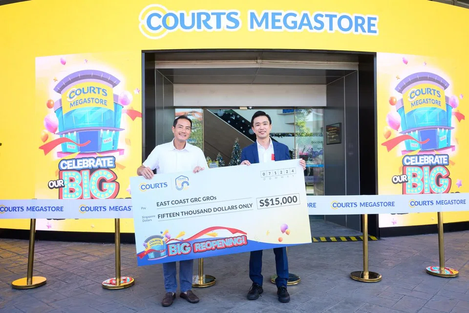 Ketua Pegawai Eksekutif COURTS, Encik Harry Higashiura (kanan), menyerahkan ‘cek’ kepada penasihat pertubuhan akar umbi GRC East Coast, Encik Tan Kiat How (kiri), semasa sambutan ulang tahun ke-50 COURTS di COURTS Megastore@Tampines pada 7 Disember.