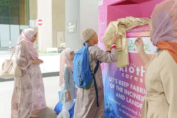 Orang awam memasukkan pakaian yang tidak digunakan ke dalam tong Kloth Cares untuk dikitar semula di Masjid Al-Falah. - Muis