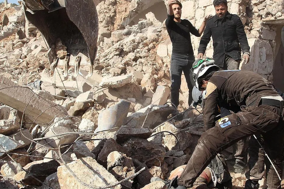 GOTONG-ROYONG BANTU MANGSA: Anggota pertahanan awam Syria yang dikenali juga dengan gelaran 'Topi Keledar Putih' mencari mangsa serangan udara dan kemudian membawa mayat mereka ke tempat yang disiapkan khas. Serangan itu berlaku di sebuah kampung, Al-Malajah. - Foto AFP