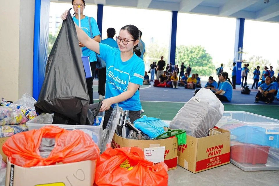 Cik Natasha Mohammad Zain memegang peralatan dan barang keperluan bagi projek Blossom Home Refresh sebagai sebahagian usaha membersihkan kediaman warga emas dan keluarga kurang bernasib baik di Marsiling.