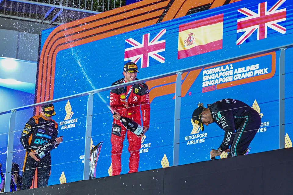 GEMBIRA: Pemandu Ferrari Carlos Sainz (tengah) meraikan kemenangan Grand Prix Formula 1 Singapura 2023 pada Ahad bersama Lando Norris dari McLaren (kiri) dan pemandu Mercedes Lewis Hamilton.