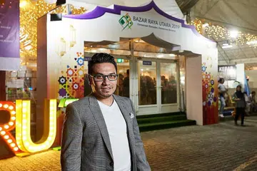 TERUS TARIK PENGUNJUNG: Encik Mohamad Fadzlin antara pasukan daripada Megaxpress International yang membawa bazar ke kawasan utara Singapura. - Foto BH oleh ROSLEE ABDUL RAZAK