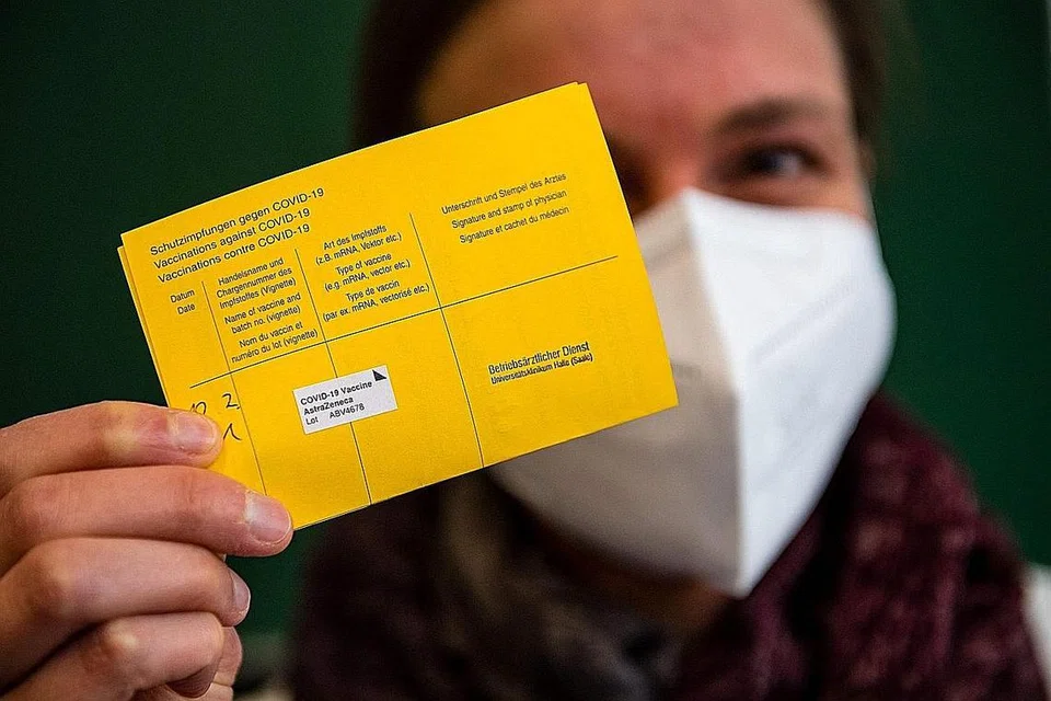 SIJIL JADI BUKTI: Seorang pekerja kesihatan di sebuah hospital di Halle/Saale, timur Jerman, menunjukkan sijil vaksinasi yang diterima selepas mendapat suntikan vaksin Covid-19. - Foto AFP