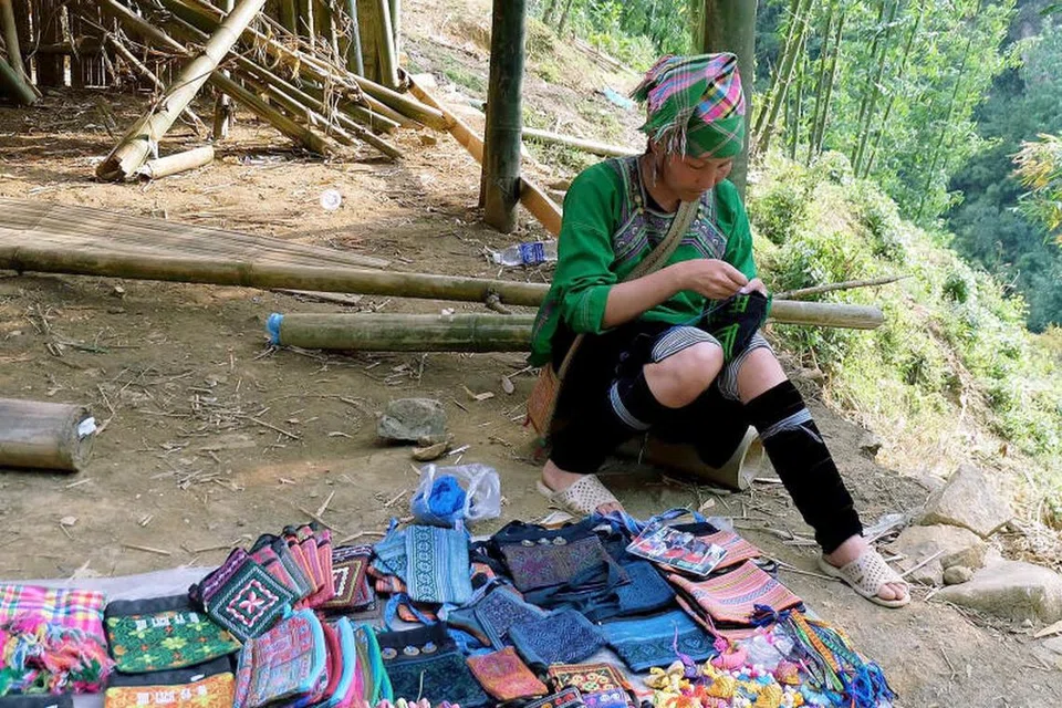 SIAPKAN KERJA SENI: Wanita ‘orang asli’ Vietnam ini sedang menjahit sulaman pada beg cendera hati buat pelancong bawa pulang.