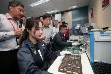 TINJAU KEMUDAHAN: Encik Khaw (tengah) melawat Kemudahan Pembaikan Kad Elektronik untuk Laluan Kereta Api ST Engineering di Boon Lay semalam. - Foto BH oleh KELVIN CHNG