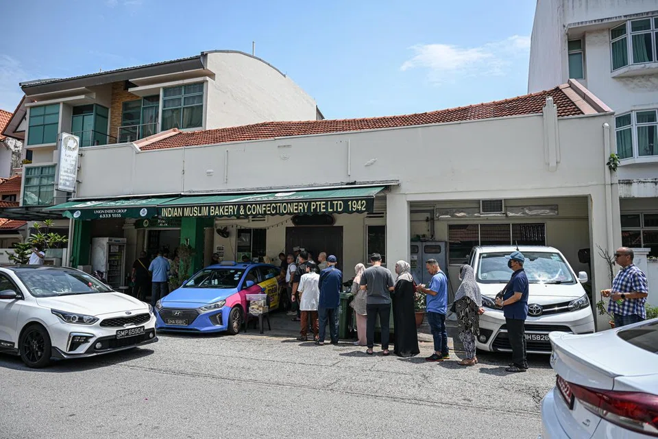 BERATUR PANJANG: Barisan panjang melimpah ke jalan dan kaki lima di luar kedai Indian Muslim Bakery & Confectionery Pte Ltd di Onan Road semalam, apabila pelanggan menanti untuk membeli karipap dan juadah lain sebelum kedai itu berhenti operasi pada Ahad.