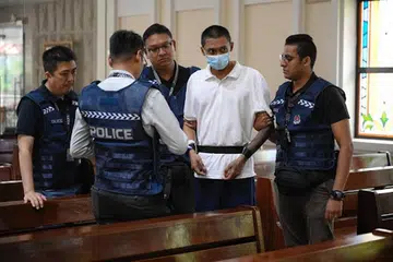 Basnayake Keith Spencer (memakai pelitup), suspek yang ditahan kerana didakwa mencederakan seorang paderi dari Gereja St Joseph’s, dibawa semula ke tempat kejadian pada 6 Disember.