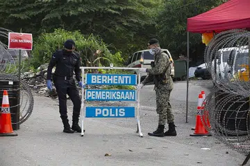 KAWALAN PERGERAKAN: Anggota pasukan keselamatan mengawal pintu masuk ke kawasan yang menjalani PKP di Kuala Lumpur, pada 5 Julai lalu. Malaysia kini menghadapi lebih 6,000 kes baru jangkitan Covid-19 sejak seminggu lalu. - Foto EPA-EFE