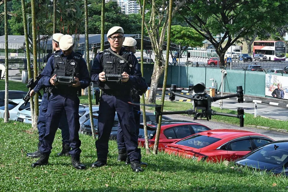 Pegawai dari Komand Keselamatan Perlindungan (ProCom) sedang mengemudi dron DJI M30T (kanan) yang digunakan untuk mengesan ‘penjenayah’ semasa latihan simulasi insiden di Ulu Pandan Road pada 22 Jun. Dron tersebut dilengkapi dengan sistem pengimejan terma dan digunakan dalam operasi keselamatan awam termasuk memburu suspek dan misi mencari dan menyelamat.