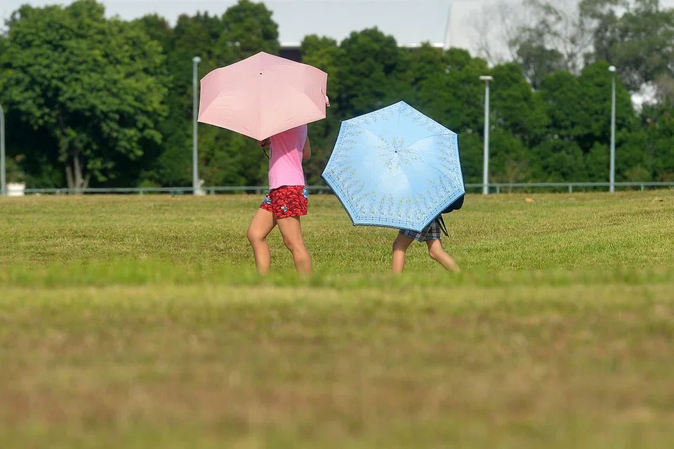 BERLINDUNG DARIPADA PANAS: Penduduk membawa payung untuk berlindung daripada panas di Bishan. - Foto THE STRAITS TIMES