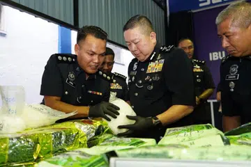 Pengarah Jabatan Siasatan Jenayah Narkotik (JSJN) Bukit Aman, Datuk Khaw Kok Chin (tengah), meneliti dadah yang dirampas dalam serbuan polis di kondominium mewah di Kajang, Selangor.
