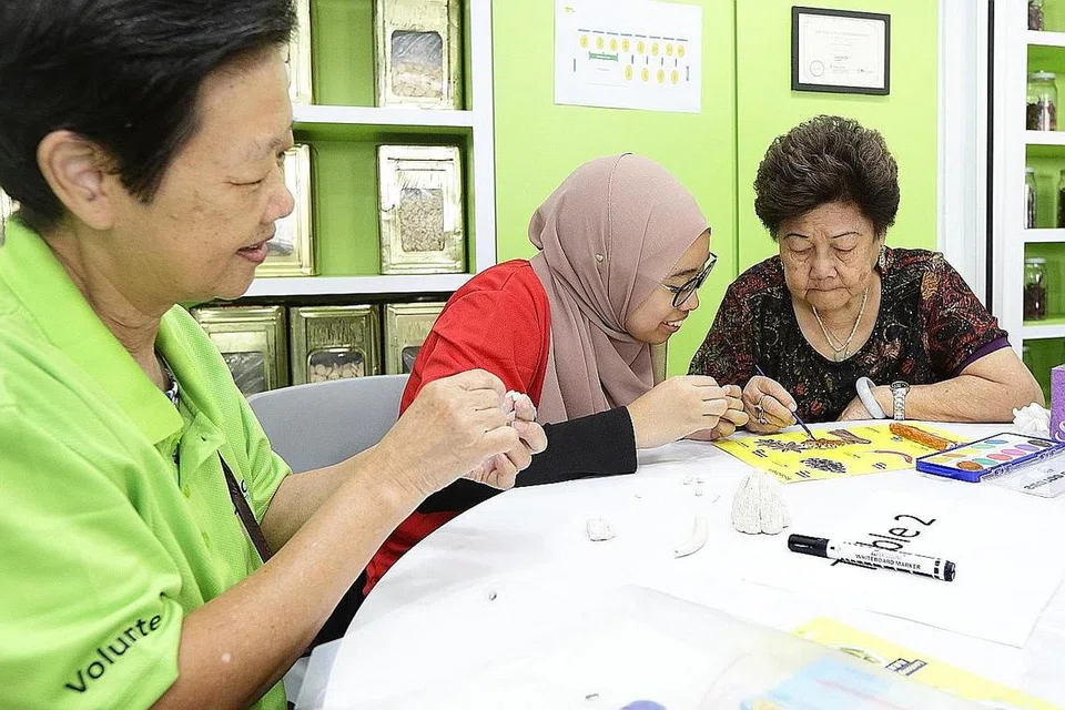 MENYUMBANG TENAGA: Cik Nadiah (tengah, gambar kanan) meluangkan masa cuti sekolahnya sebagai sukarelawan. Beliau menganggap menggunakan seni dalam kerja sukarela adalah sesuatu yang segar.