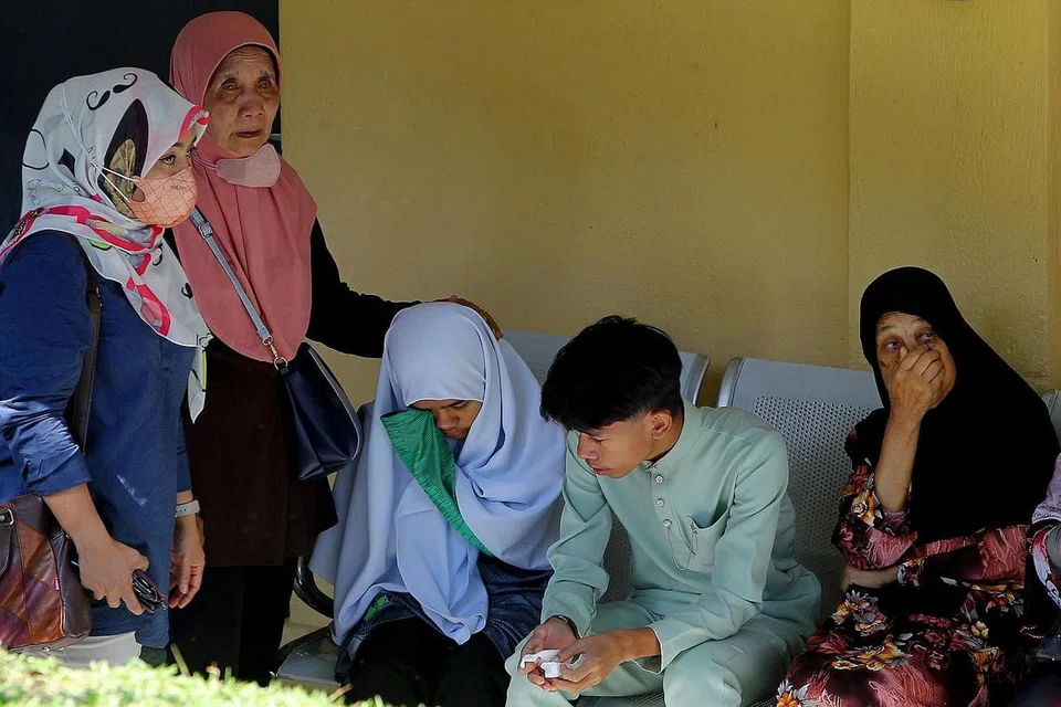 PILU: Ahmad Danish Basyir Nasaruddin (dua dari kanan) dan adiknya, Siti Nur Khadijah (tiga dari kanan) dipujuk ahli keluarga ketika menunggu jenazah adik-beradik dan ibu mereka di Unit Forensik Hospital Kampar pada 16 Mei lalu. - Foto BERNAMA