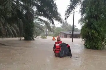 DIPINDAHKAN: Anggota bomba memindahkan mangsa bah di Kampung Bukit Dagang di Ulu Tiram menyusuli hujan berterusan di Johor sejak 3 Disember.