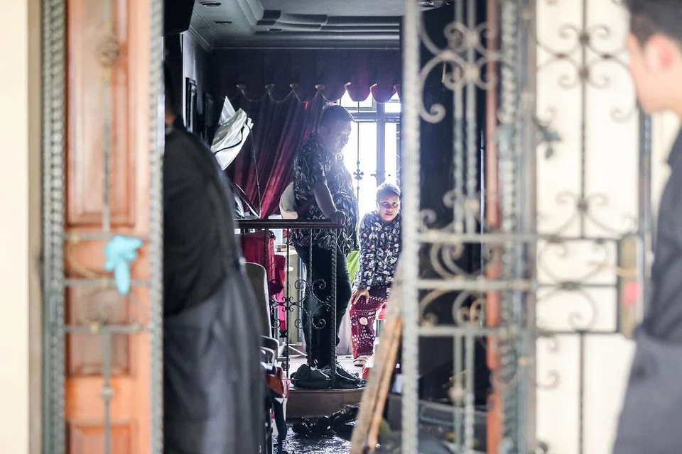 SEDIH LIHAT KEADAAN FLAT: Beberapa anggota keluarga flat empat bilik di Blok 340A Sembawang Close kelihatan meninjau keadaan rumah semalam selepas ia mengalami kebakaran petang kelmarin.