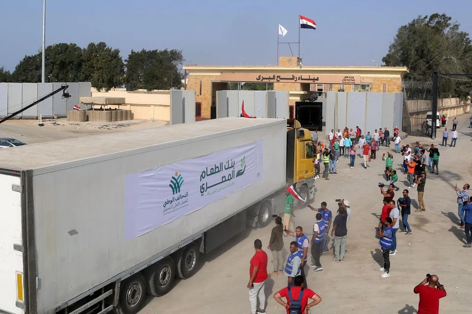 BANTUAN KEMANUSIAAN: Para penduduk di bahagian wilayah Mesir di lintasan Rafah, melihat  trak yang membawa bantuan kemanusiaan bergerak masuk ke Gaza pada Ahad. 