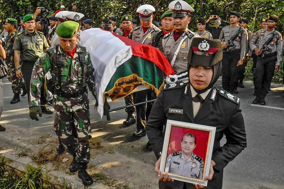 UPACARA PENGEBUMIAN: Anggota pasukan polis Indonesia mengusung keranda pegawai yang terkorban dalam serangan pengganas ke atas sebuah ibu pejabat polis di Pekanbaru. - Foto AFP