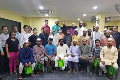 USAHA BERTERUSAN: Ustaz Leyaket Ali Mohamed Omar, anggota RRG (barisan kedua, dengan kain sandang), bergambar dengan pekerja asing dan pegawai kanan dari Kementerian Ehwal Dalam Negeri, termasuk Setiausaha Parlimen Kanan Encik Amrin Amin (barisan kedua, tengah) di satu perjumpaan. - Foto RRG