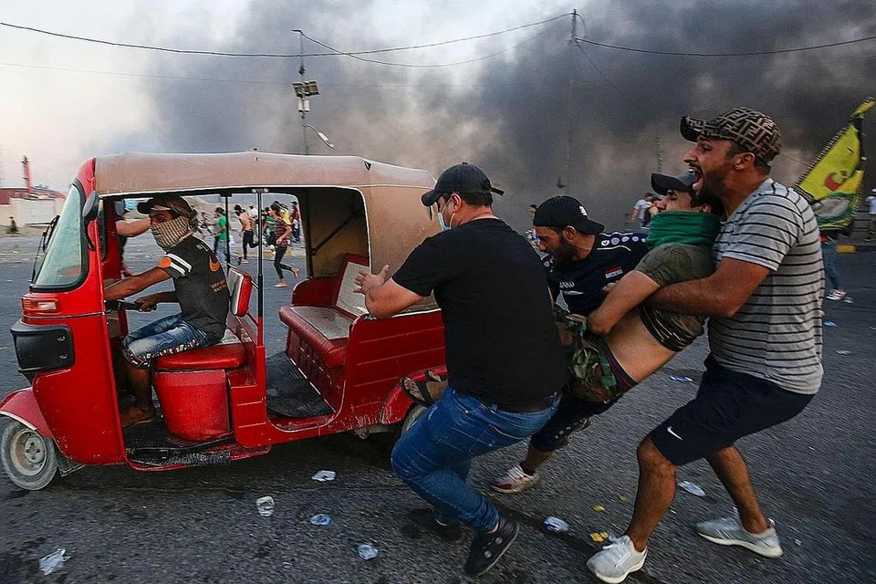 BANTU RAKAN YANG CEDERA: Sekumpulan lelaki ini membantu rakan yang cedera semasa pihak tentera cuba menyuraikan bantahan itu. - Foto AFP 