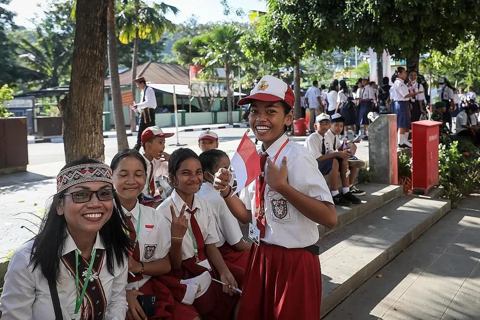 SENYUMAN BAGI TETAMU: Sekumpulan kanak-kanak menanti di tepi jalan berhampiran Pusat Konvensyen Meruorah di Labuan Bajo, Nusa Tenggara Timur, pada 10 Mei. Pusat konvensyen itu menjadi tuan rumah kepada Sidang Puncak Asean ke-42. Berbekal bendera dan senyuman gembira, mereka berada di sana untuk menyambut konvoi peserta sidang puncak dan akan melambaikan bendera dan bersorakan apabila konvoi kenderaan kelihatan. - Foto-foto ST