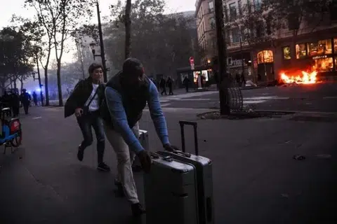 Pelancong berlari membawa bagasi mereka berhampiran Place de la Madeleine, berdekatan kebakaran yang berlaku semasa tunjuk perasaan di Paris pada 17 Oktober.