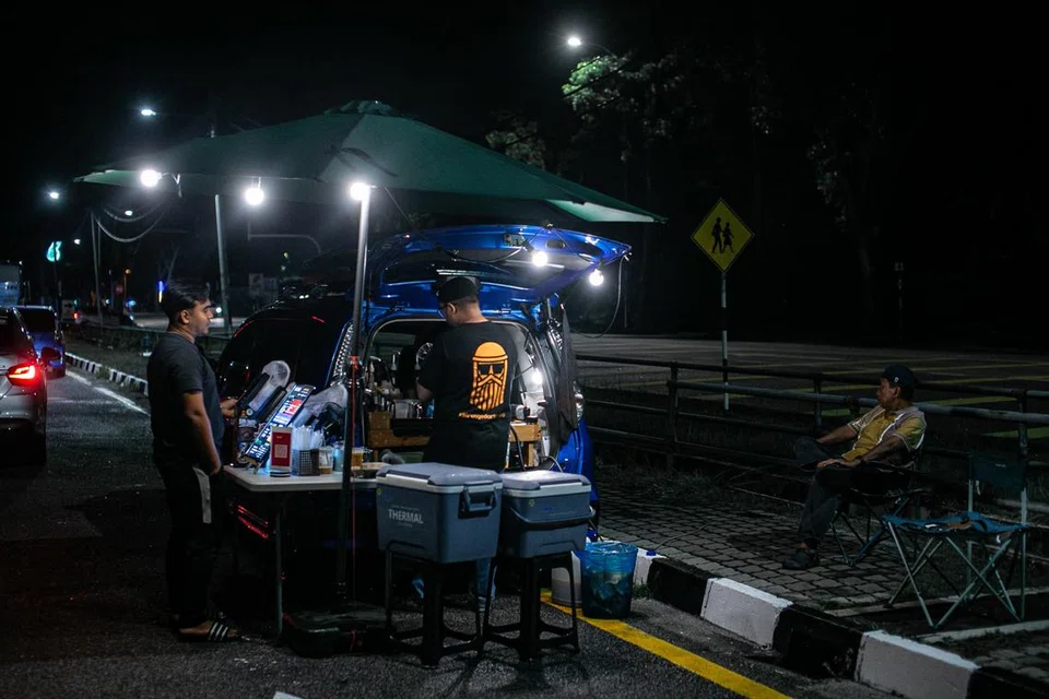 KAFE TEPI JALAN: Encik Muhammad Zulkhairi Kasim, 32 tahun, menguruskan sebuah perniagaan sambilan dari but kereta Perodua Alza miliknya.di tepi sebatang jalan raya di Pulau Pinang, dengan menyediakan kopi.