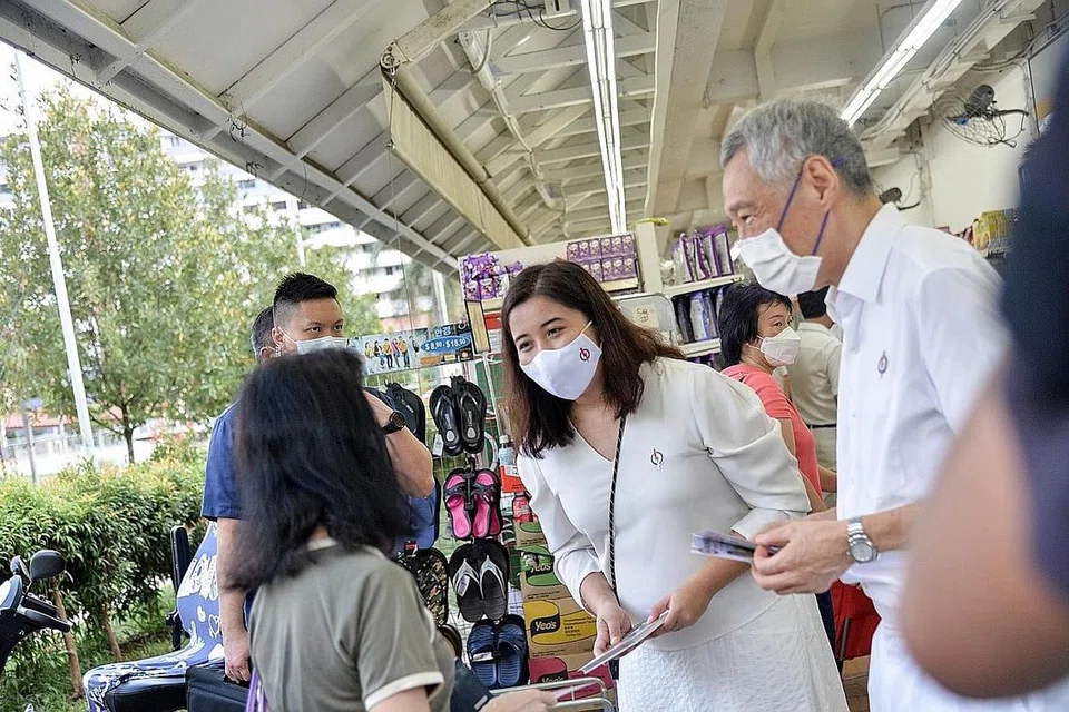 DAPAT BIMBINGAN: Cik Nadia, yang dilihat beramah dengan penduduk semasa berkempen di GRC Ang Mo Kio, akui banyak mendapat bimbingan daripada PM Lee (kanan). - Foto BH oleh HARITH MUSTAFFA