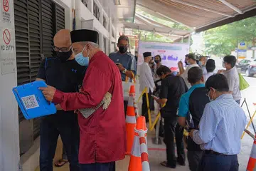 TUNJUK BUKTI: Jemaah yang mempunyai bukti vaksinasi sepenuhnya yang sah yang dikesan menerusi aplikasi TraceTogether oleh kakitangan masjid akan menunjukkan warna hijau tetapi mereka yang belum divaksinasi sepenuhnya, ia akan menunjukkan warna merah. - Foto BH oleh MARK CHEONG