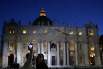 Orang ramai bergambar di depan Gereja St. Peter - tempat mesyuarat para kardinal berlangsung bagi memilih paus atau pope yang baru. 