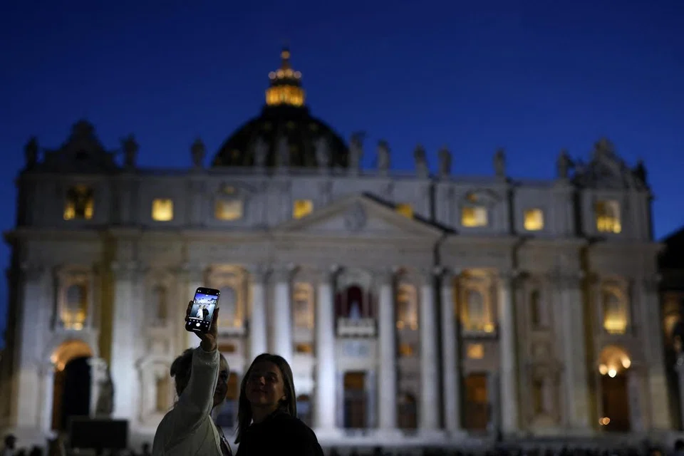 Orang ramai bergambar di depan Gereja St. Peter - tempat mesyuarat para kardinal berlangsung bagi memilih paus atau pope yang baru. 