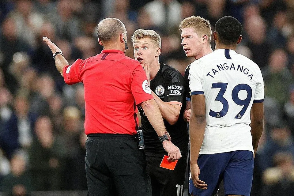 HADAPI TINDAKAN: Pemain Manchester City, Oleksandr Zinchenko (depan pengadil) memberi reaksi selepas dilayangkan kad kuning kedua dan seterusnya dikenakan kad merah oleh pengadil Mike Dean, yang menandakan pemain itu perlu keluar padang sambil diperhatikan oleh Kevin De Bruyne (dua dari kanan) dan pemain Tottenham Hotspur, Japhet Manzambi Tanganga. - Foto Reuters