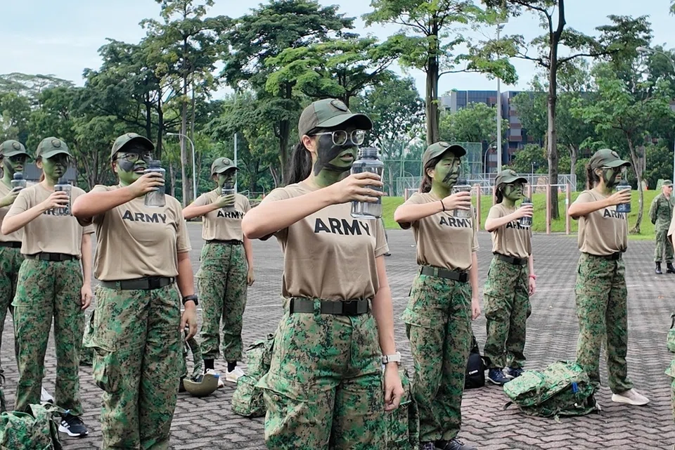 Peserta Kem Latihan Wanita (WBC) melakukan ‘water parade’ (perintah meminum air sebanyak mungkin supaya mengelakkan penyahhidratan) sambil melafazkan lapan nilai teras Angkatan Bersenjata Singapura (SAF). 