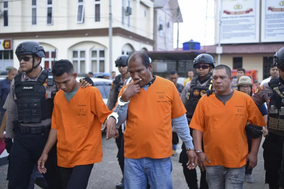 PENDUDUK ACEH DITAHAN: Anggota polis mengiringi tiga suspek pemerdagangan manusia warga Indonesia kerana disyaki membantu pelarian Rohingya meninggalkan kem mereka, di ibu pejabat polis di Lhokseumawe, Sumatera.