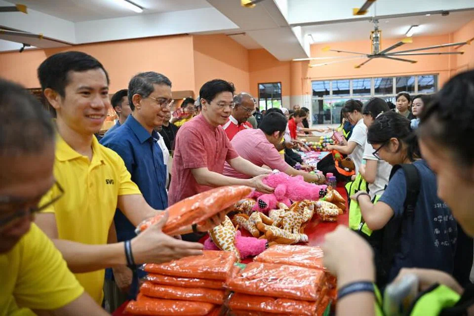 Perdana Menteri, Encik Lawrence Wong (tengah) bersama Menteri Ehwal Dalam Negeri merangkap Undang-Undang, Encik K. Shanmugam (enam dari kiri) dan Menteri Negara (Ehwal Dalam Negeri merangkap Pembangunan Negara), Profesor Madya Dr Muhammad Faishal Ibrahim (baju biru) membantu sukarelawan membungkus ‘Kidz Care Pack’ yang akan diberikan kepada mangsa kanak-kanak di Gaza.