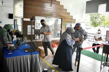 LANGKAH SELAMAT: Alat imbas suhu badan disediakan bagi memudahkan jemaah memasuki masjid selain menyediakan beg plastik bagi jemaah meletakkan kasut mereka sekiranya mereka terlupa untuk membawanya. - Foto-foto BH oleh KHALID BABA
